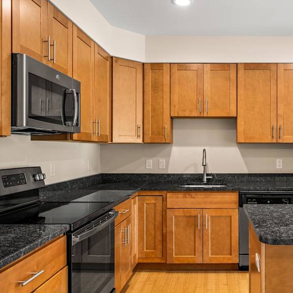 a kitchen with wooden cabinets and black countertops.