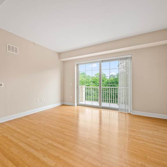 a room with wooden floors and a sliding glass door leading to a balcony.