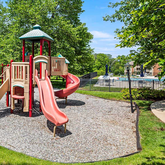 a playground with a red slide and a green roofed structure.