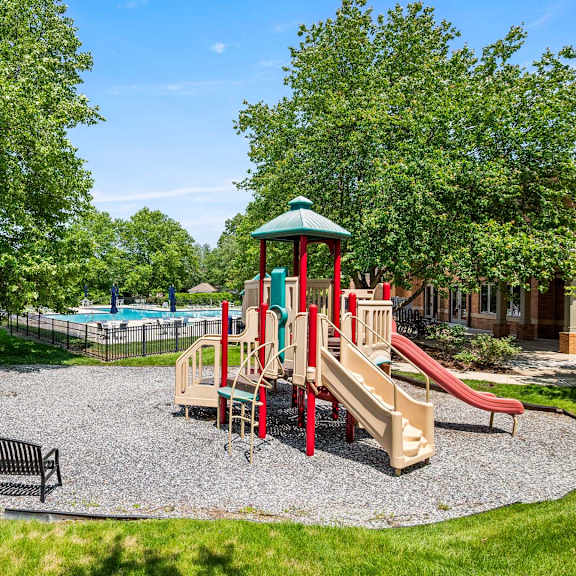 a playground with a slide, swings, and a bench.