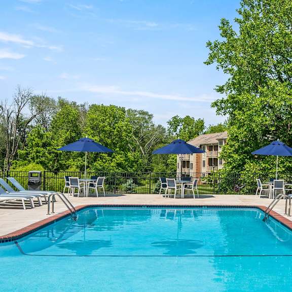 a swimming pool surrounded by lawn chairs and umbrellas.