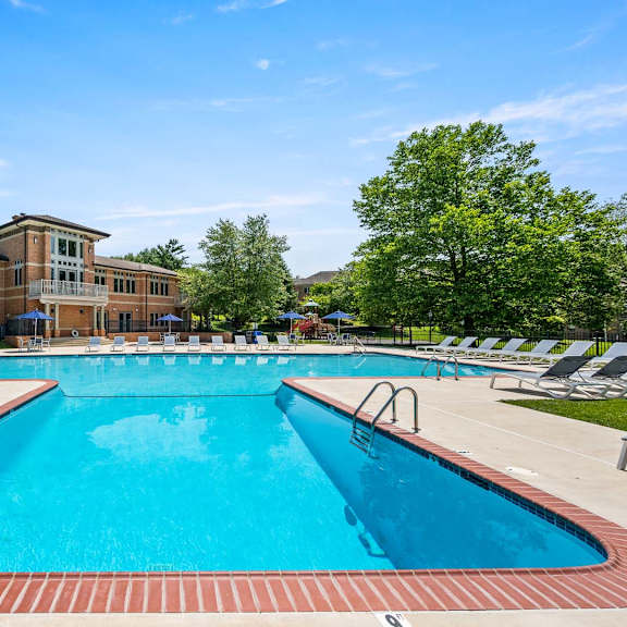 a large swimming pool with a red brick border and a building in the background.