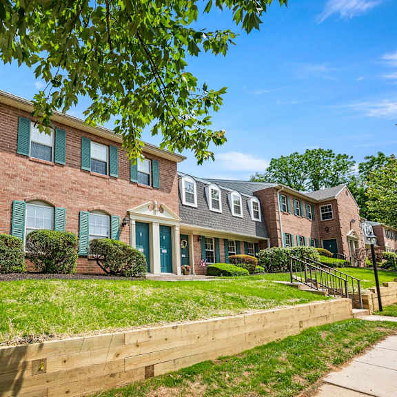 a row of houses with green shutters and a blue sky above.