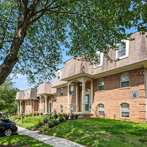 a house with a brick facade and a tree in front.
