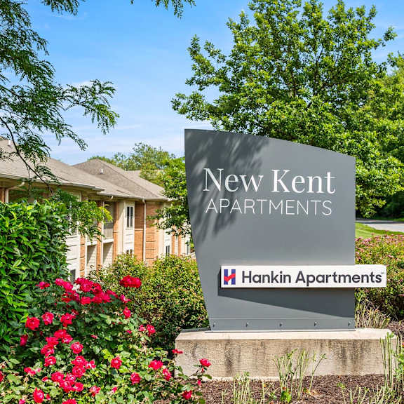 a sign for new kent apartments by hankin apartments stands in front of a building.