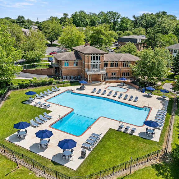 a large swimming pool surrounded by lawn chairs and umbrellas.