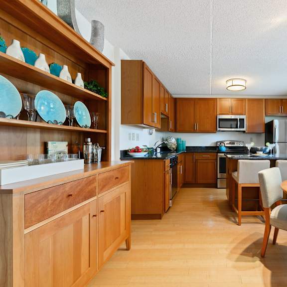 a kitchen and dining area with hardwood-style flooring, stainless steel appliances, and two windows in the deluxe tahoe floor plan at new kent apartments in west chester, pa