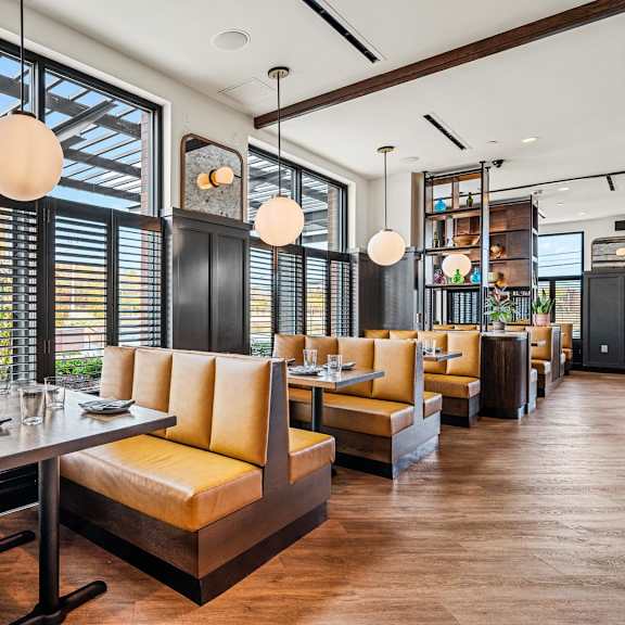 a restaurant with a long table and chairs with a view of the street outside.