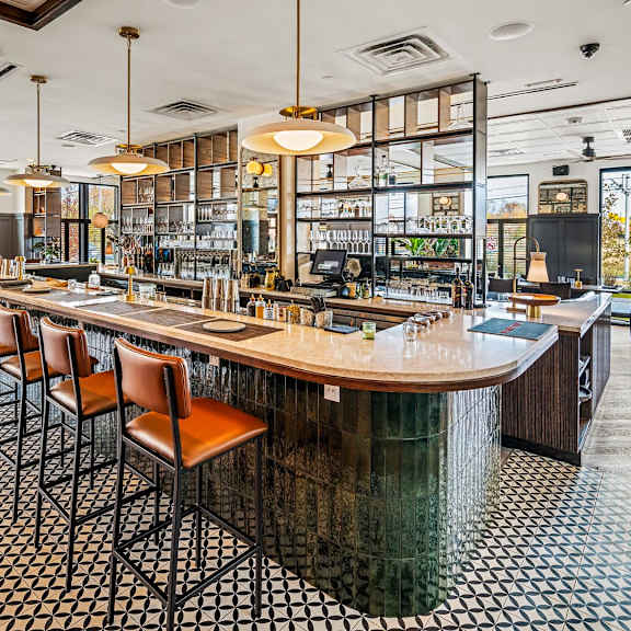a bar with a long wooden counter and chairs.