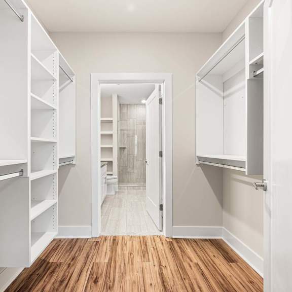 a white walk in closet with shelves and a doorway.