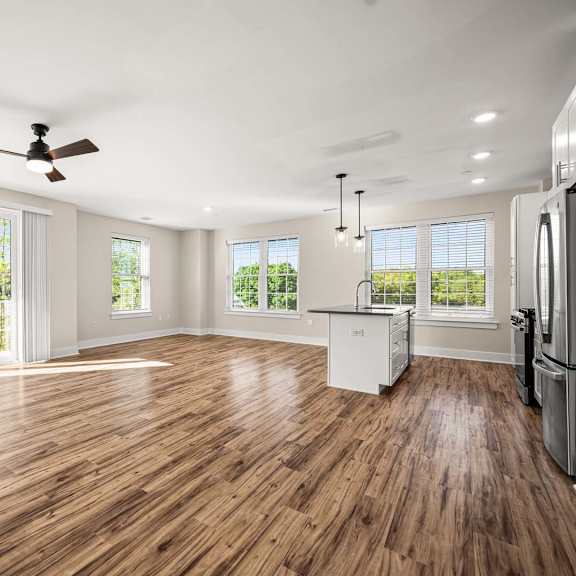 a spacious kitchen with wooden floors and a ceiling fan.