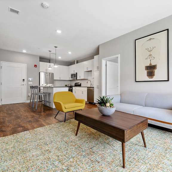 luxury exton apartment living room featuring wood-inspired flooring, a spacious open-concept layout, and direct access to a modern kitchen with an oversized island at claremont on the square.