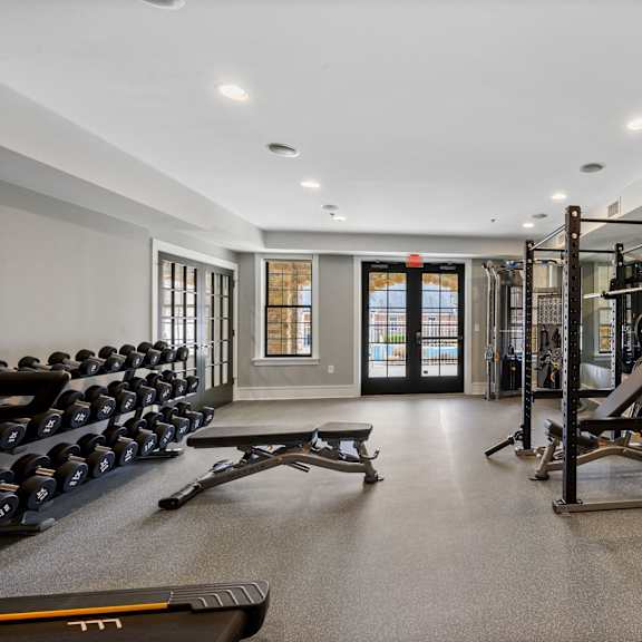 a gym with a variety of equipment including dumbbells, weight plates, and benches.