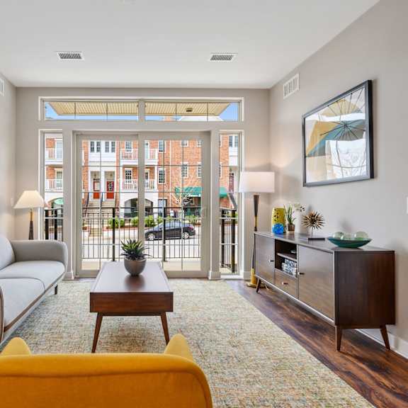 bright luxury apartment living room with wood-inspired flooring and views of a spacious private patio overlooking eagleview town center’s walkable dining, shops, and everyday conveniences at claremont