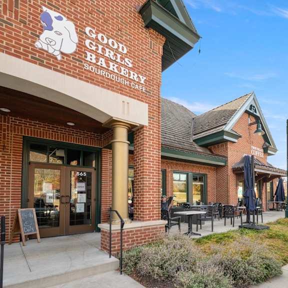 a brick building with a sign that says good girls bake sourdough cafe.
