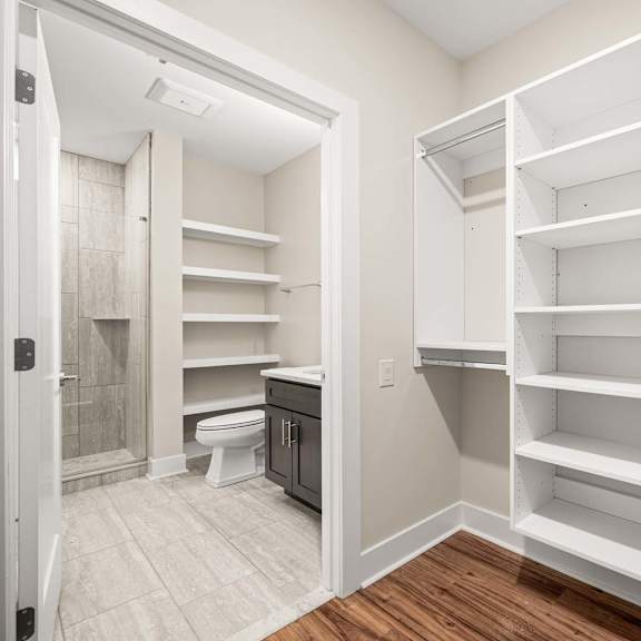 a white walk-in closet with shelves and a toilet in the corner.