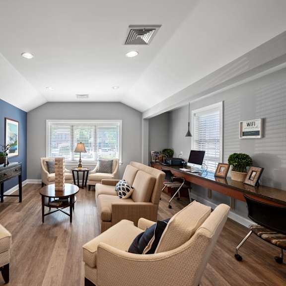 a clubhouse with two windows, hardwood-style flooring, comfortable seating areas, and a flat-screen tv.