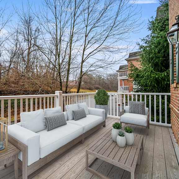 wooden deck with a white couch and cozy pillows, offering a relaxing outdoor space at claremont apartments in exton, pa