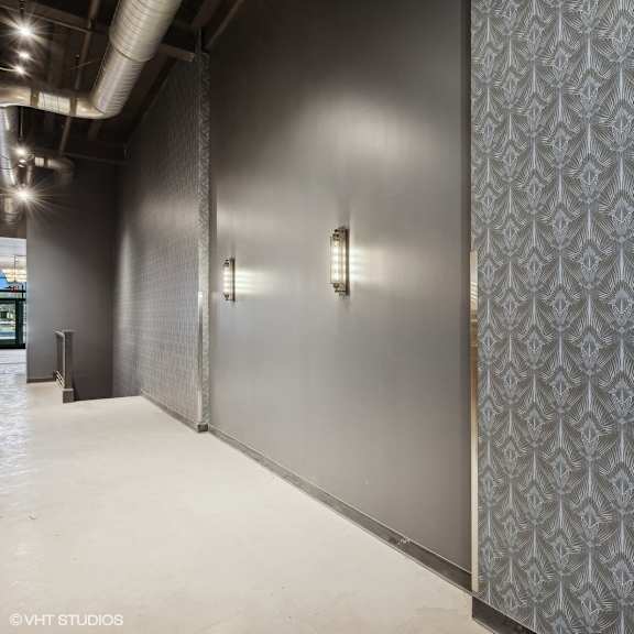 a hallway with a patterned wallpaper and two wall lights.