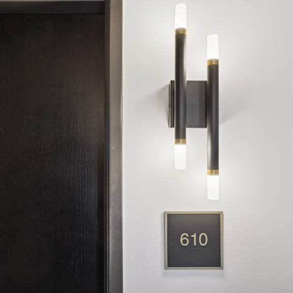 a black door with a wall light above it.