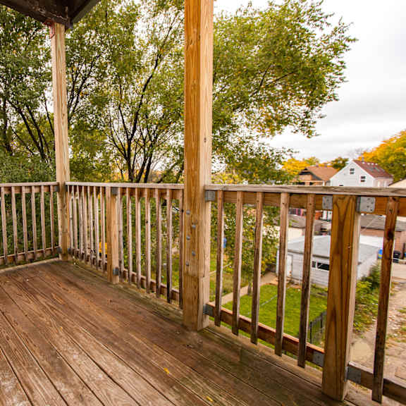 the deck of a home with wooden railing and trees