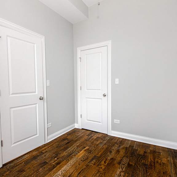 an empty room with two doors and wood floors