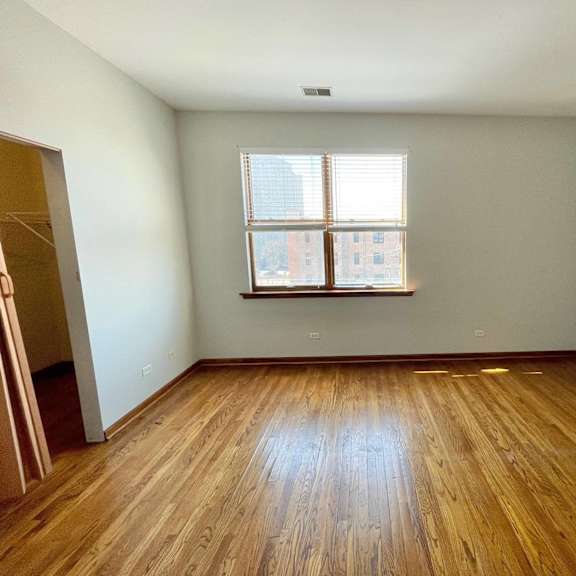 an empty room with wooden floors and a window