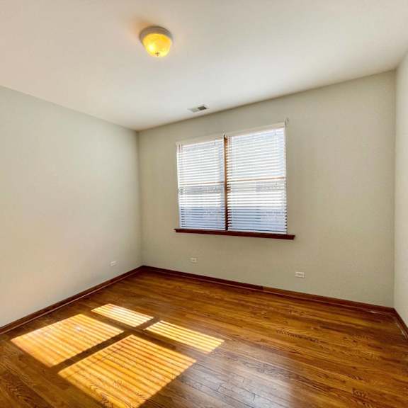 an empty room with hardwood floors and a window