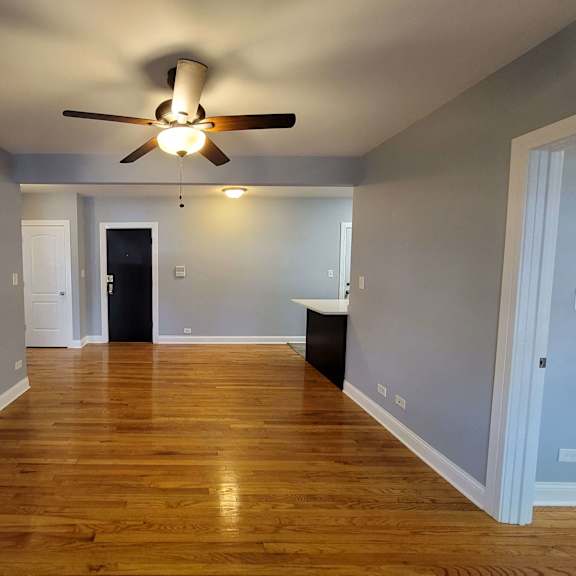 a empty living room with a ceiling fan and wood floors