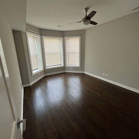 an empty room with a ceiling fan and three windows