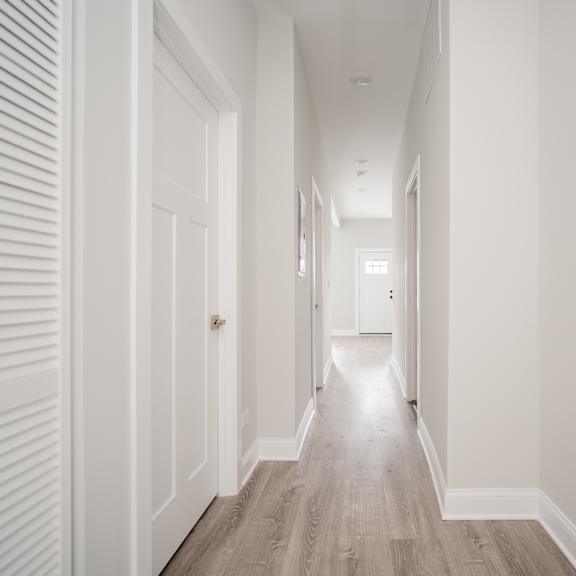 a hallway with white walls and wooden floors and white doors