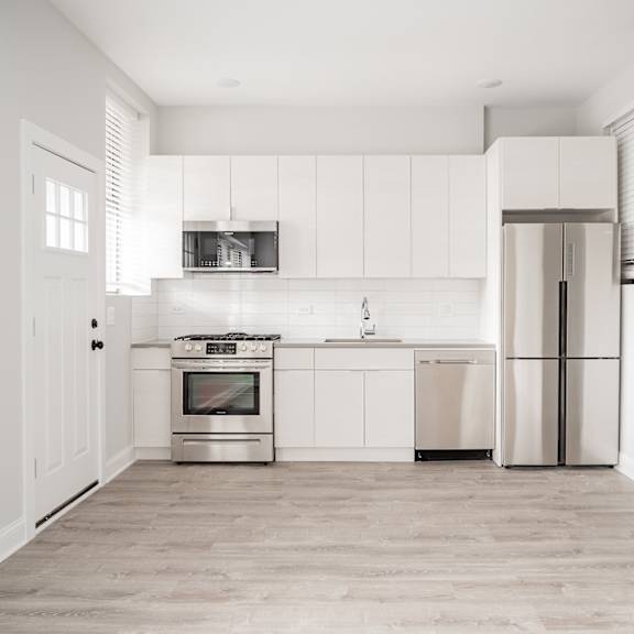 a white kitchen with stainless steel appliances and white cabinets