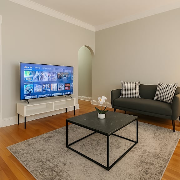 a living room with a black couch, a television, and a coffee table.