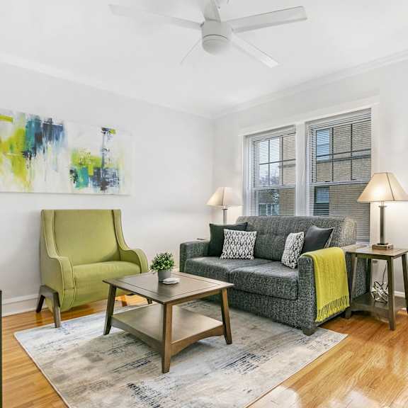 a living room with a couch and a chair and a ceiling fan