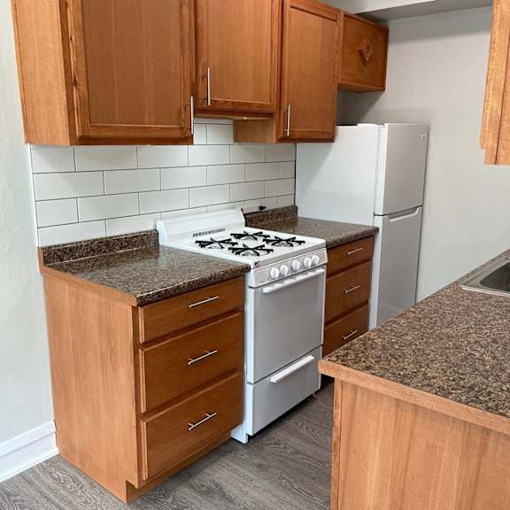 an empty kitchen with wooden cabinets and a stove and refrigerator