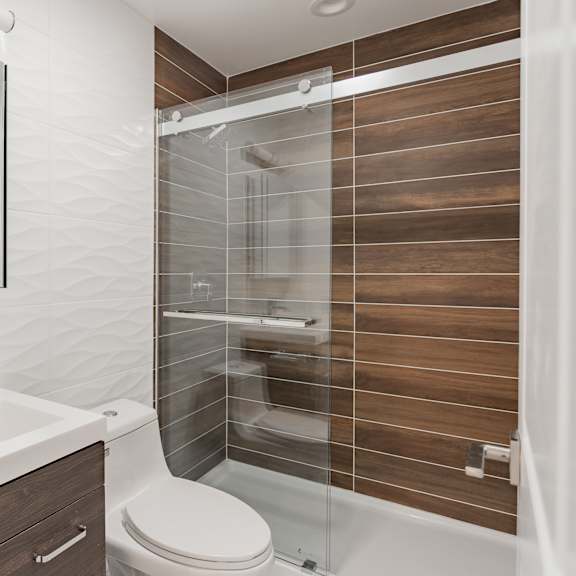 a modern bathroom with a walk-in shower and a white sink.