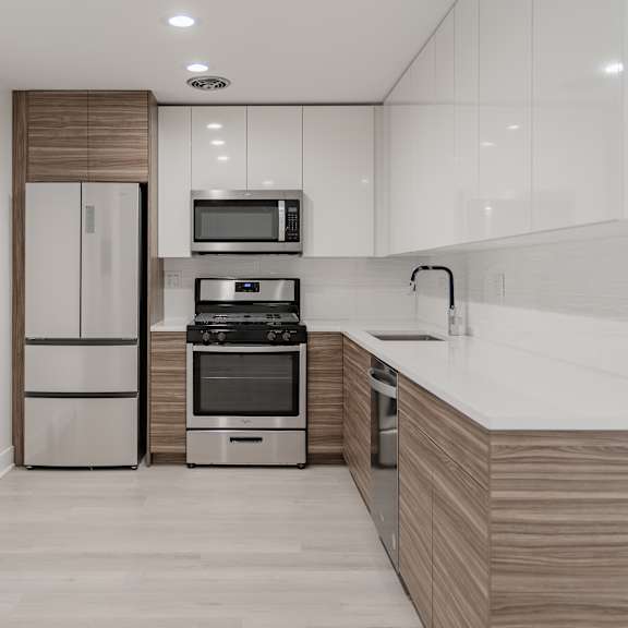 a modern kitchen with a refrigerator, microwave, oven, and sink.