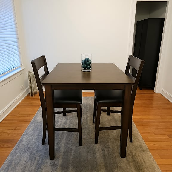 a brown dining table with two chairs and a glass of water on it.