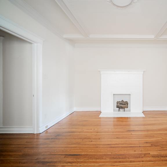 a living room with white walls and a fireplace and wooden floors