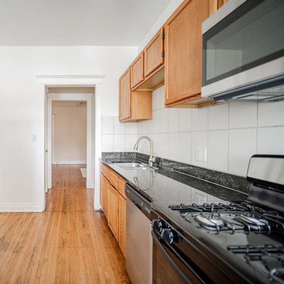 an empty kitchen with stainless steel appliances and wooden cabinets