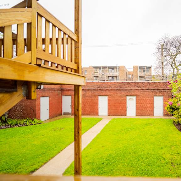a view of the yard of a brick building with a wooden deck