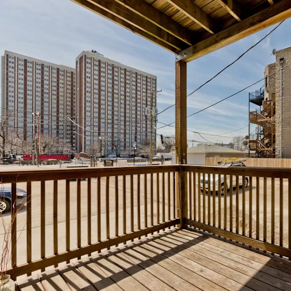 a wooden deck with a railing and a view of a cityscape.