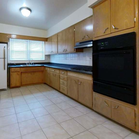 a kitchen with a black microwave above the stove and a white refrigerator.