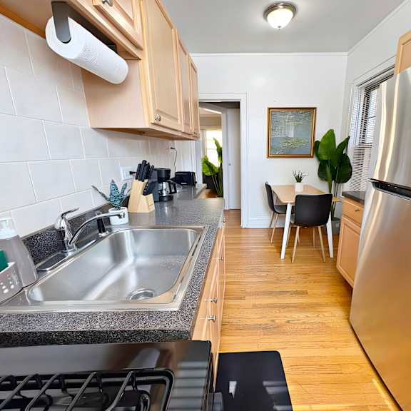 a modern kitchen with a stainless steel refrigerator and a dining area with a table and chairs.