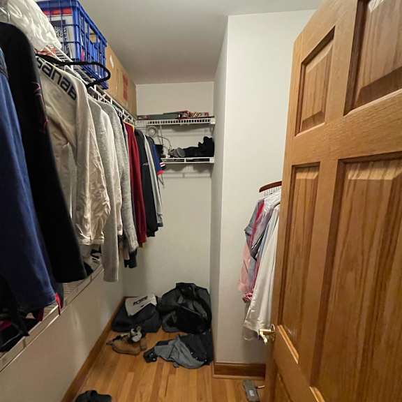 a hallway with a wooden door and clothes hanging on a rack.