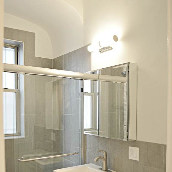 a small bathroom with a shower and a sink and a mirror