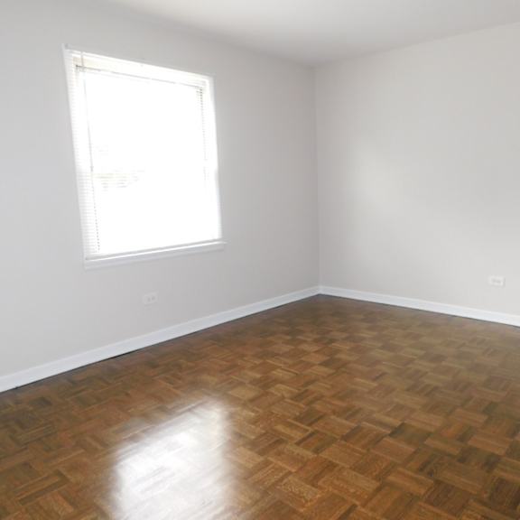 a room with a wooden floor and a window letting in light.