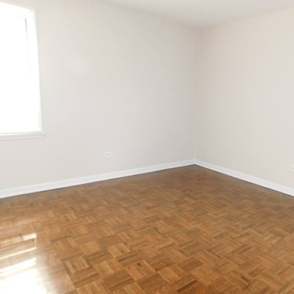 a room with wooden flooring and two windows.