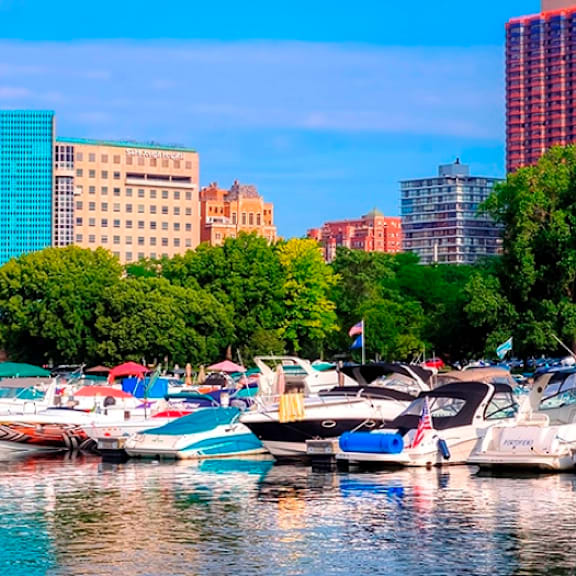 a red boat is docked in a marina with other boats and buildings in the background.