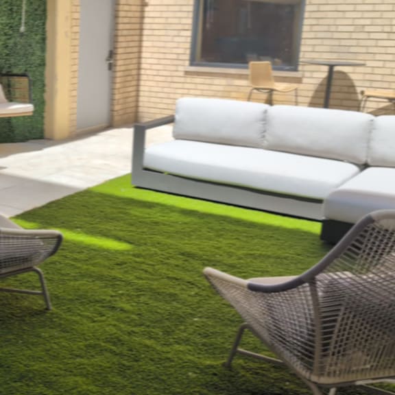 a patio with a white couch, a green rug, and a chair.